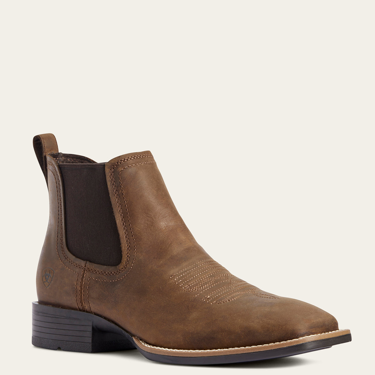 Ariat Booker Ultra Men’s Western Chelsea boot in distressed tan full-grain leather featuring a square toe, elastic side panels, a 1.5-inch stockman heel, and a rubber outsole.