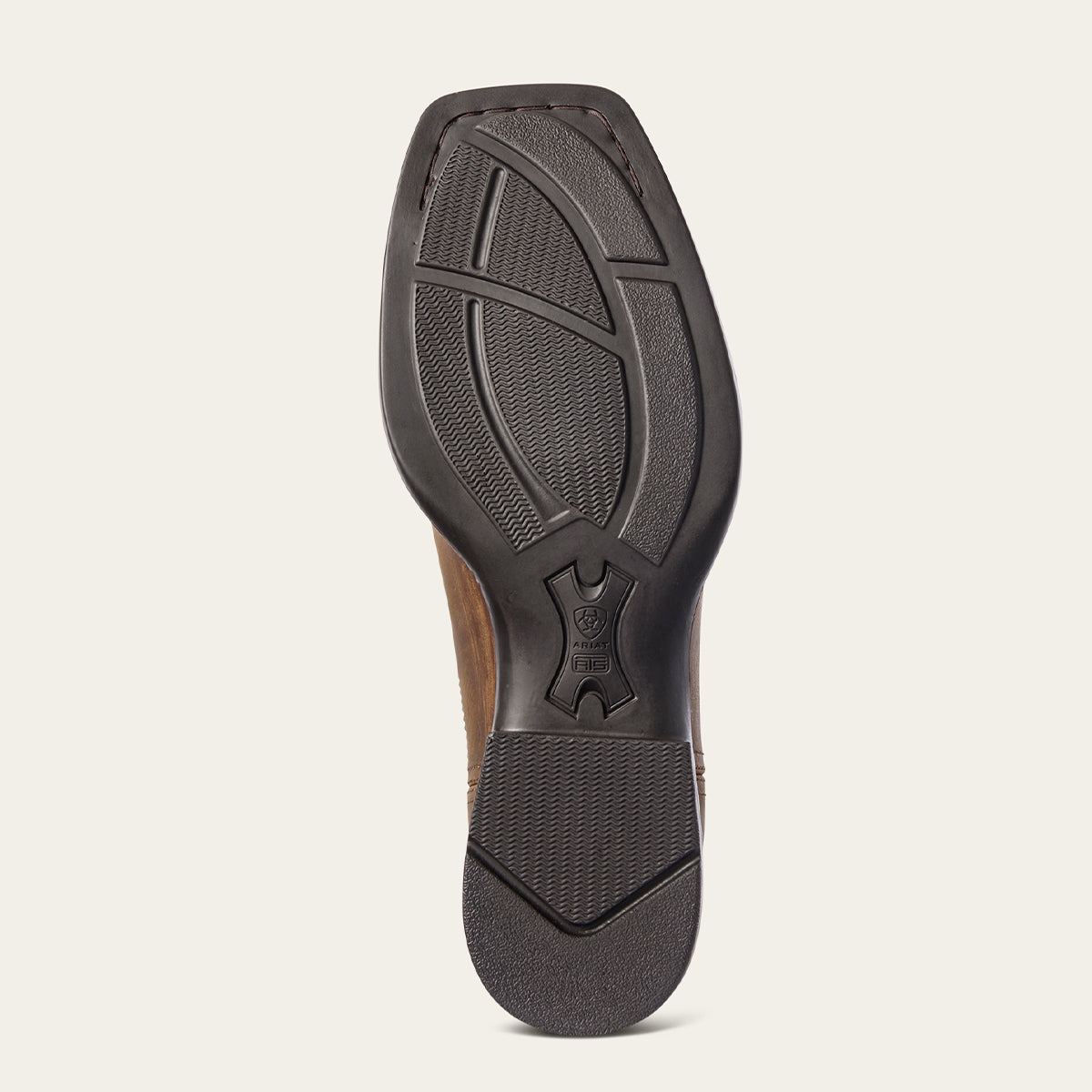 The outsole of a brown leather Ariat boot with a black rubber tread, shown from a top-down view against a light beige background.