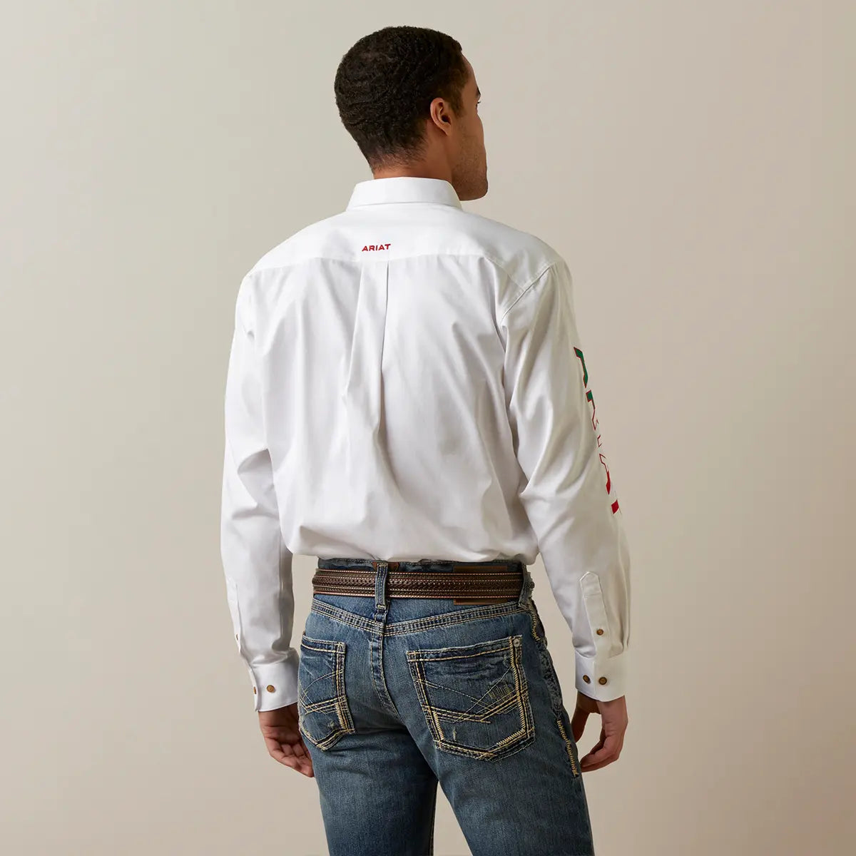 Rear view of the model showcasing the back fit of the white twill shirt and red embroidered Ariat logo on the back collar.