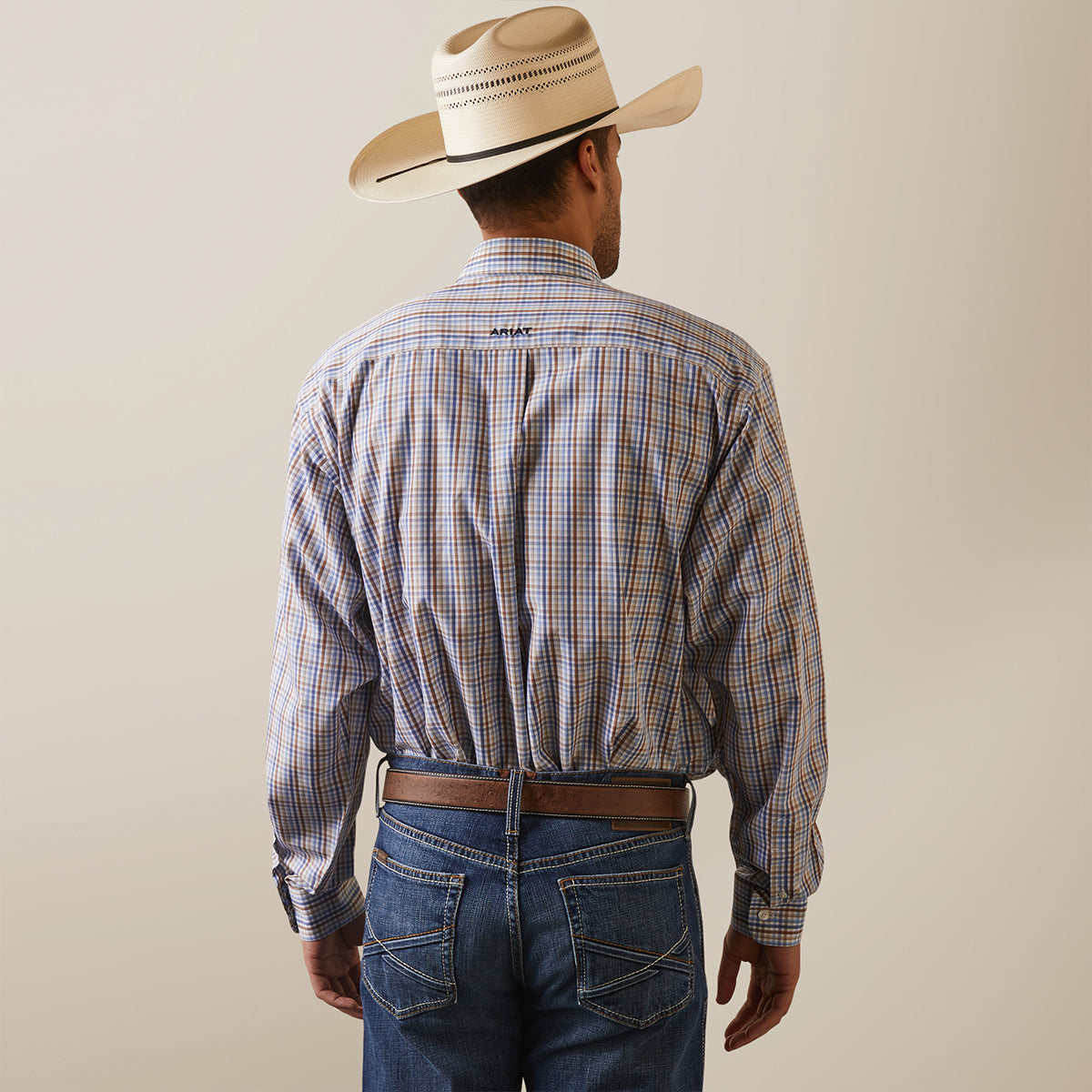 Back view of a man wearing the Ariat Men's Wrinkle Free Arther blue and brown plaid long sleeve shirt.