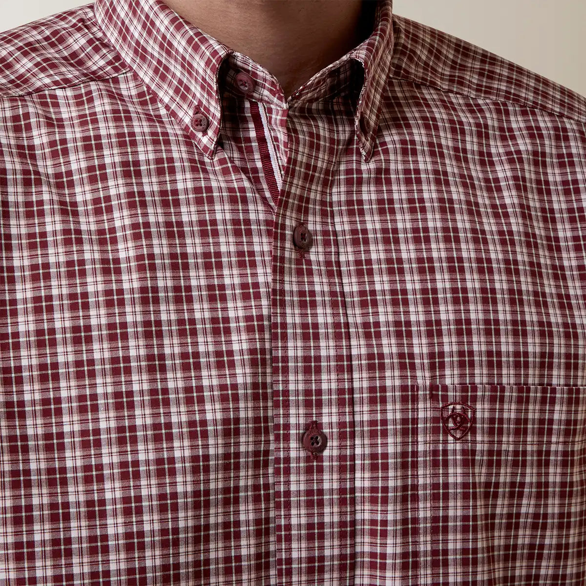 Close-up view of a man wearing the Ariat Men's Pro Series Archie maroon and white plaid long sleeve button-down shirt.