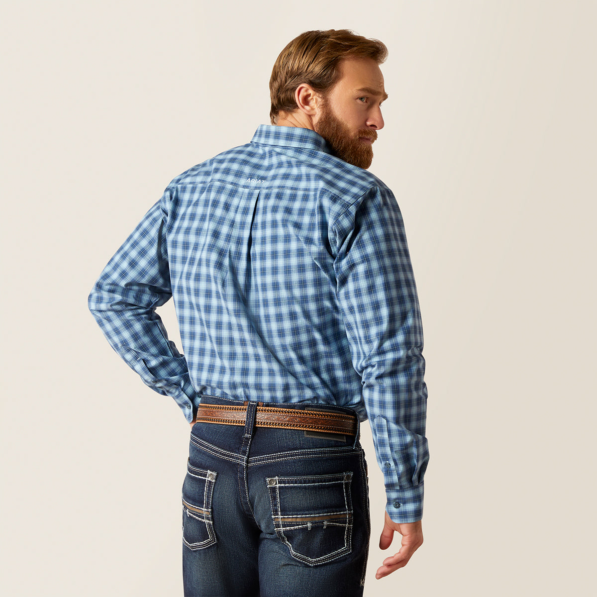 Back view of a man wearing the Ariat Men's Pro Series Gradison Sky Blue plaid long sleeve fitted button-down shirt with hat and jeans.