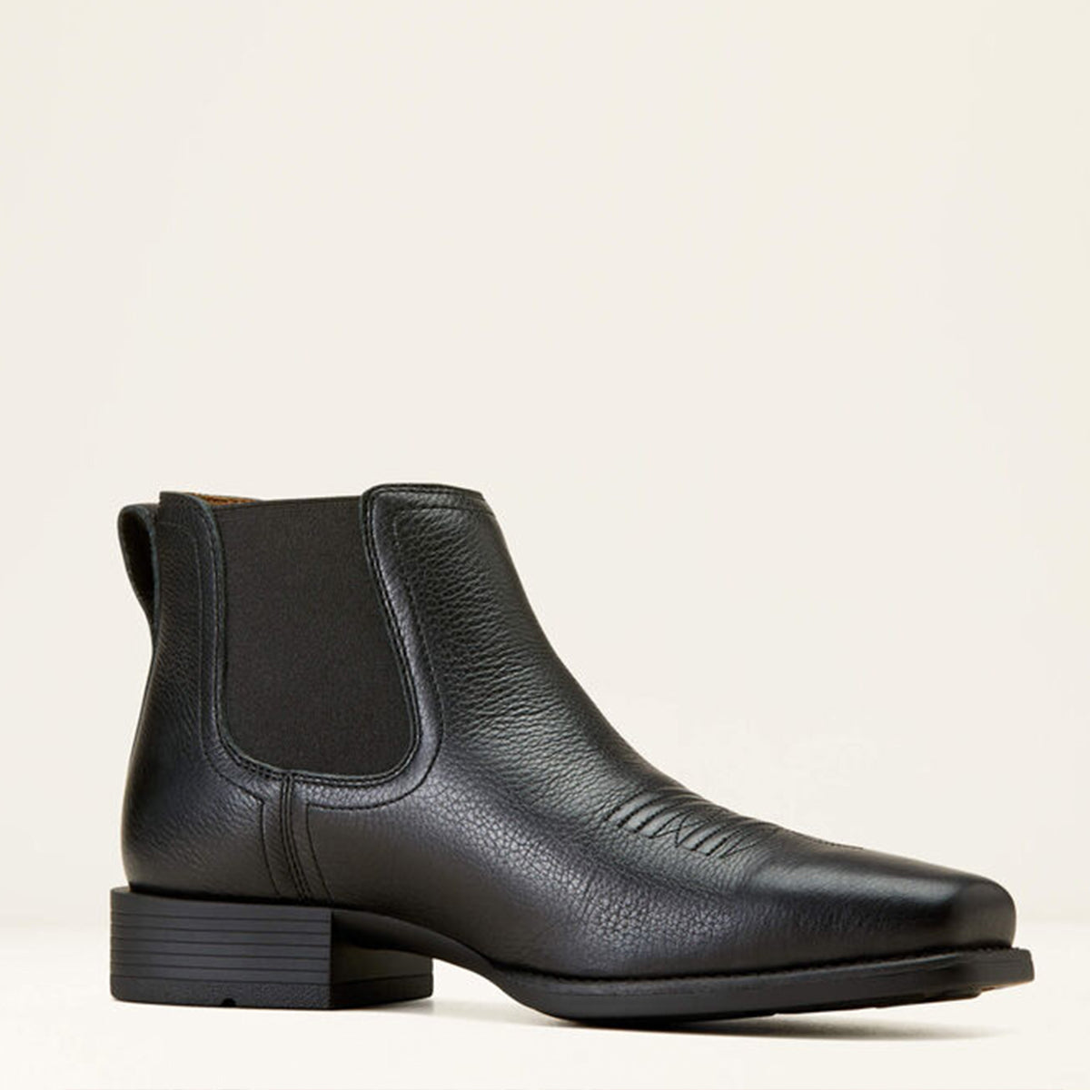 Ariat Black leather square toe Chelsea boot on a light beige background.
