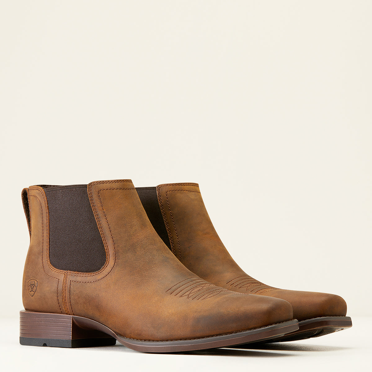 Ariat Men’s Booker Ultra Chelsea square toe western boots in brown full-grain leather featuring side elastic panels, traditional toe stitching, and a horseman heel.