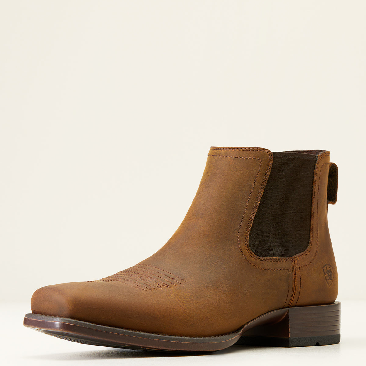 A single brown leather Ariat Chelsea boot with a dark brown elastic side gore and a low stacked heel, photographed from a side profile against a clean off-white background.