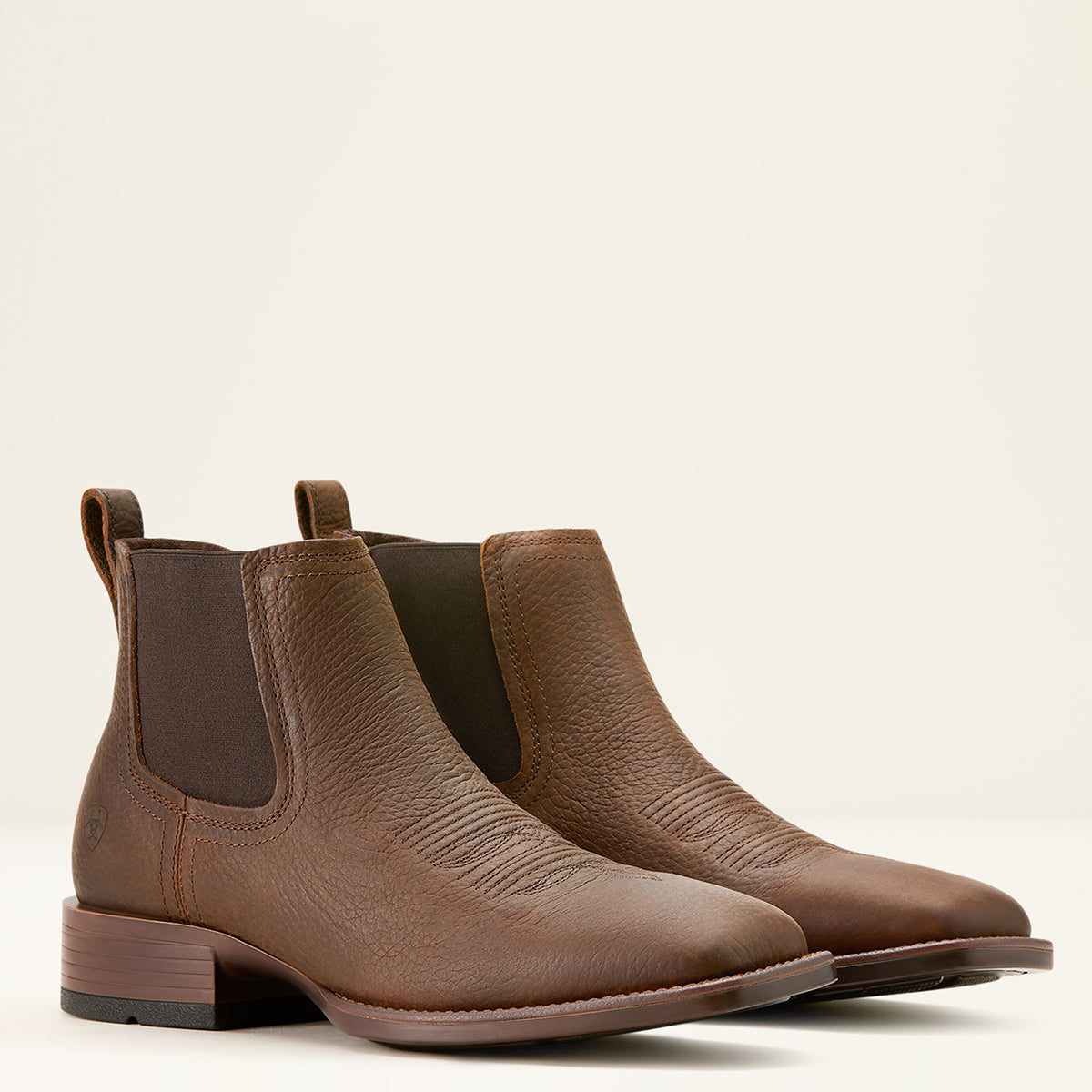 Ariat Men’s Booker Chelsea boots in Brown Oiled Rowdy pebbled leather featuring elastic side panels, front and rear pull tabs, and a square toe profile.
