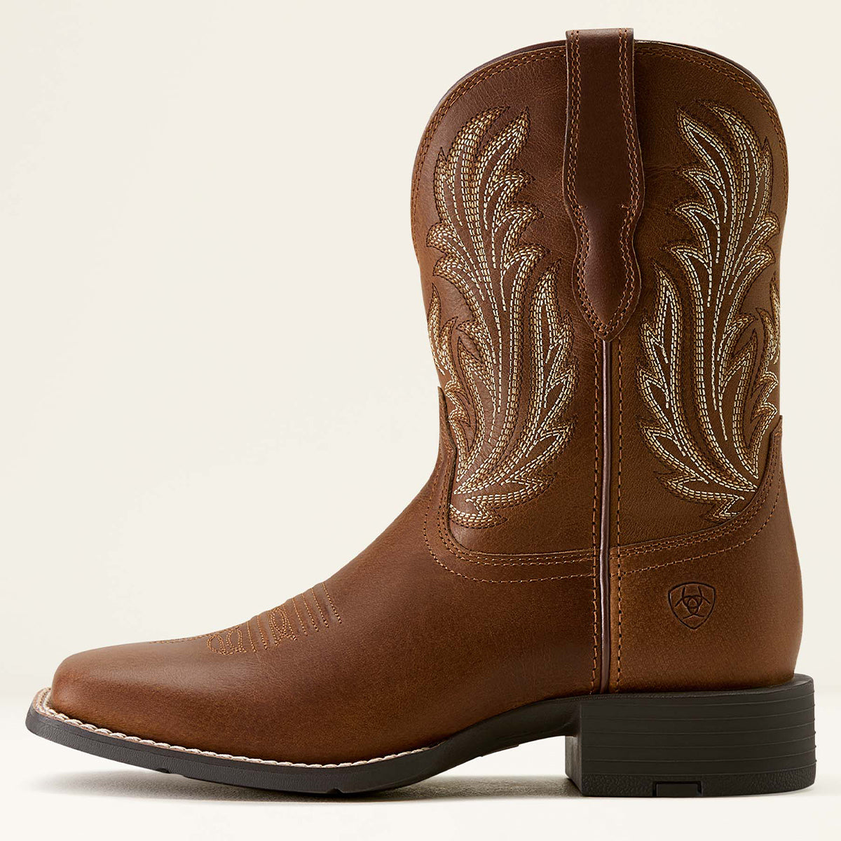 Ariat women's brown leather cowboy boot with decorative light tan embroidery on the shaft, a square toe, and a black stacked heel, shown in profile against a light beige background.