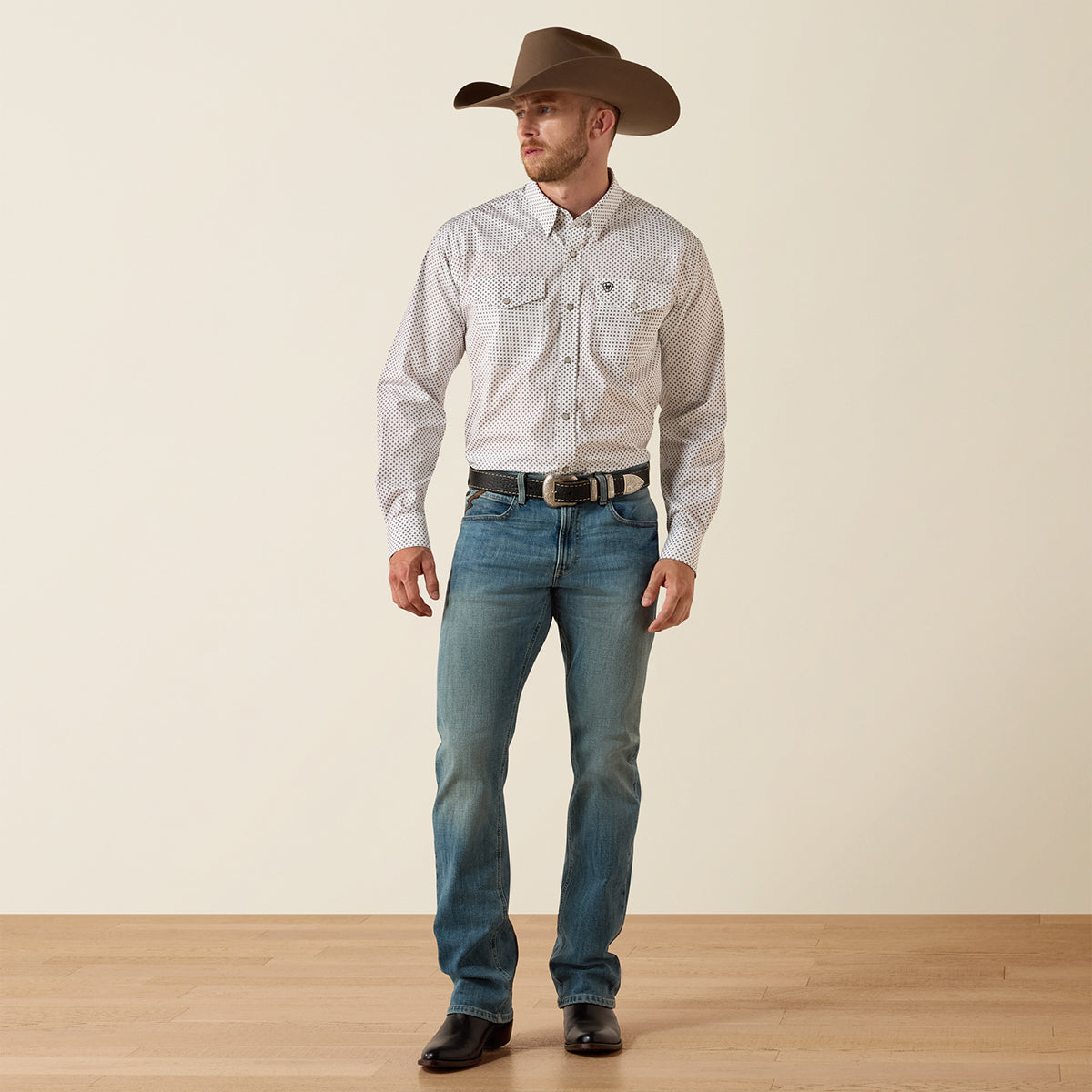 Front view of a man wearing the Ariat Men's White Anthony Wrinkle Free Classic Fit long sleeve Western pearl snap shirt with geometric micro-print.