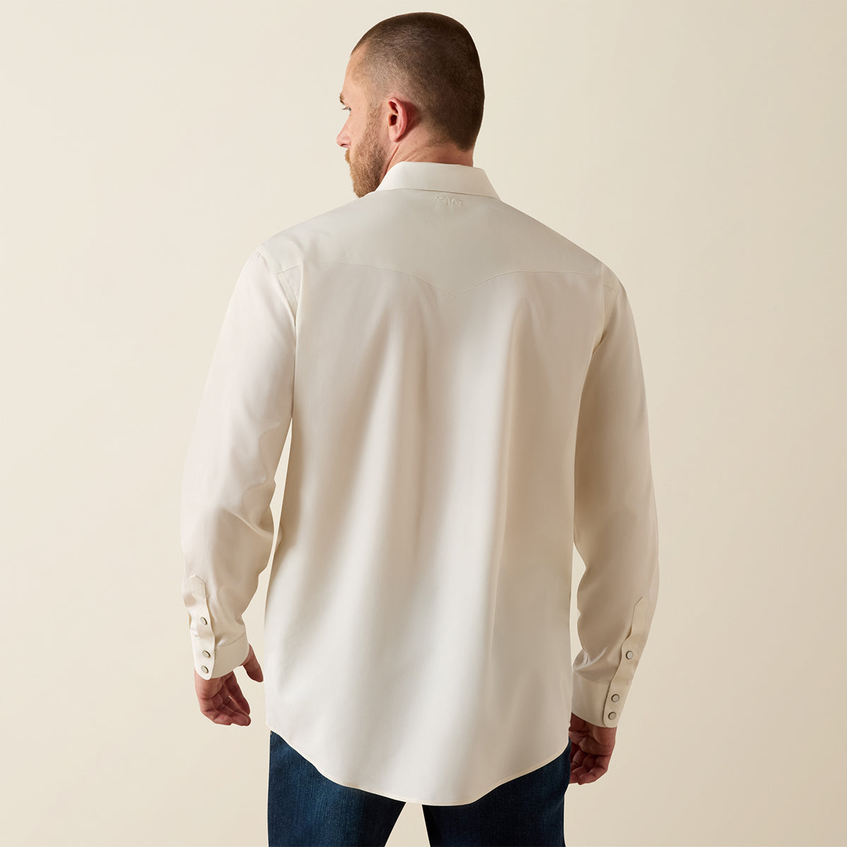 Man wearing a white long-sleeve shirt against a beige background.