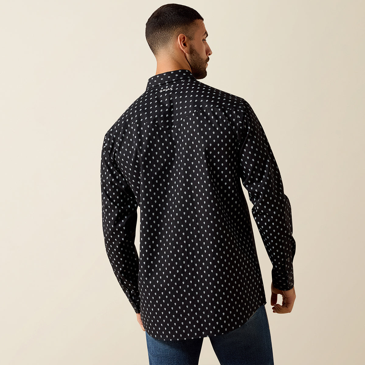 Back view of a man wearing the Ariat Men's Black Paisley Truth Fitted long sleeve Western snap shirt with chest flap pockets.