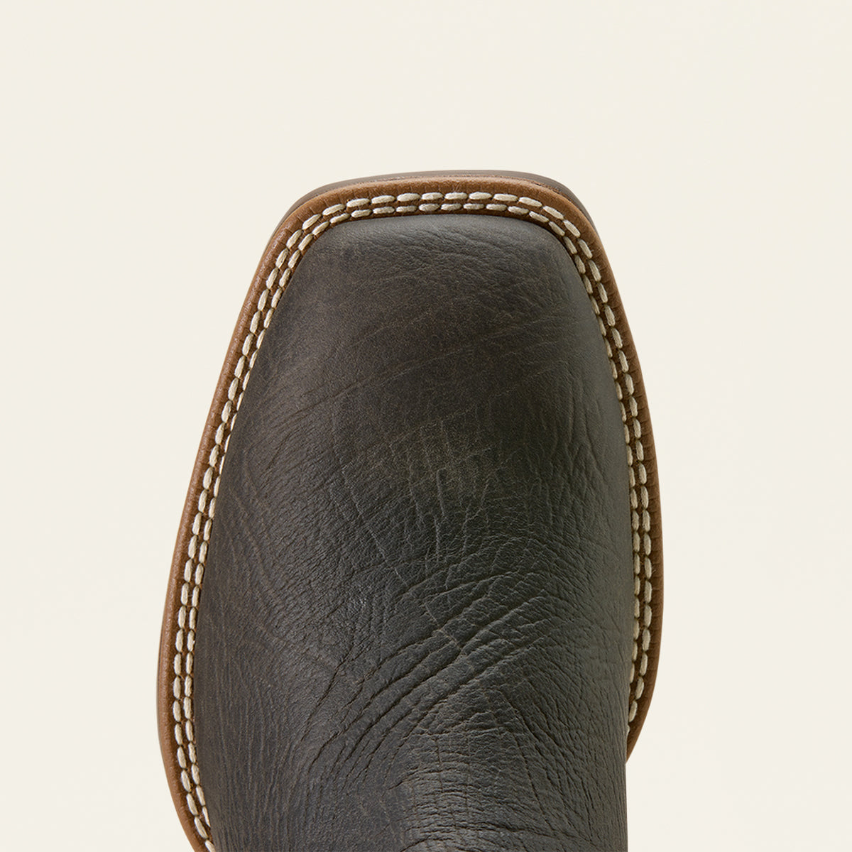 Close-up of Ariat grey leather boot square toe with light tan stitching along the edge, shown against a plain off-white background.