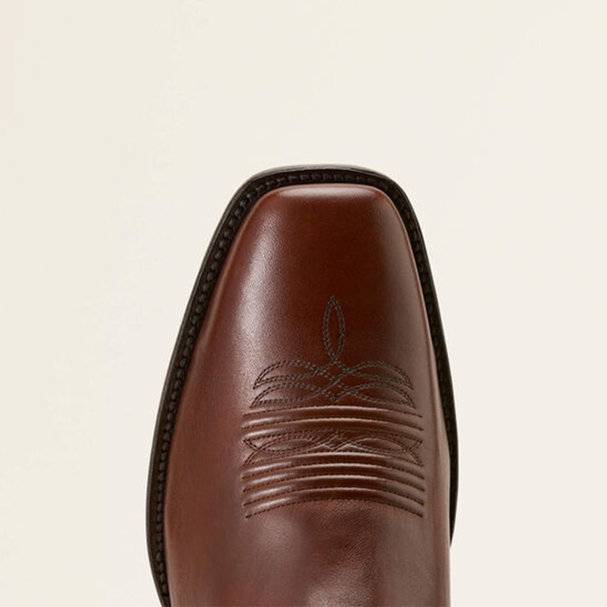 Close-up of Ariat Ridge brown boot toe profile with on a beige background.