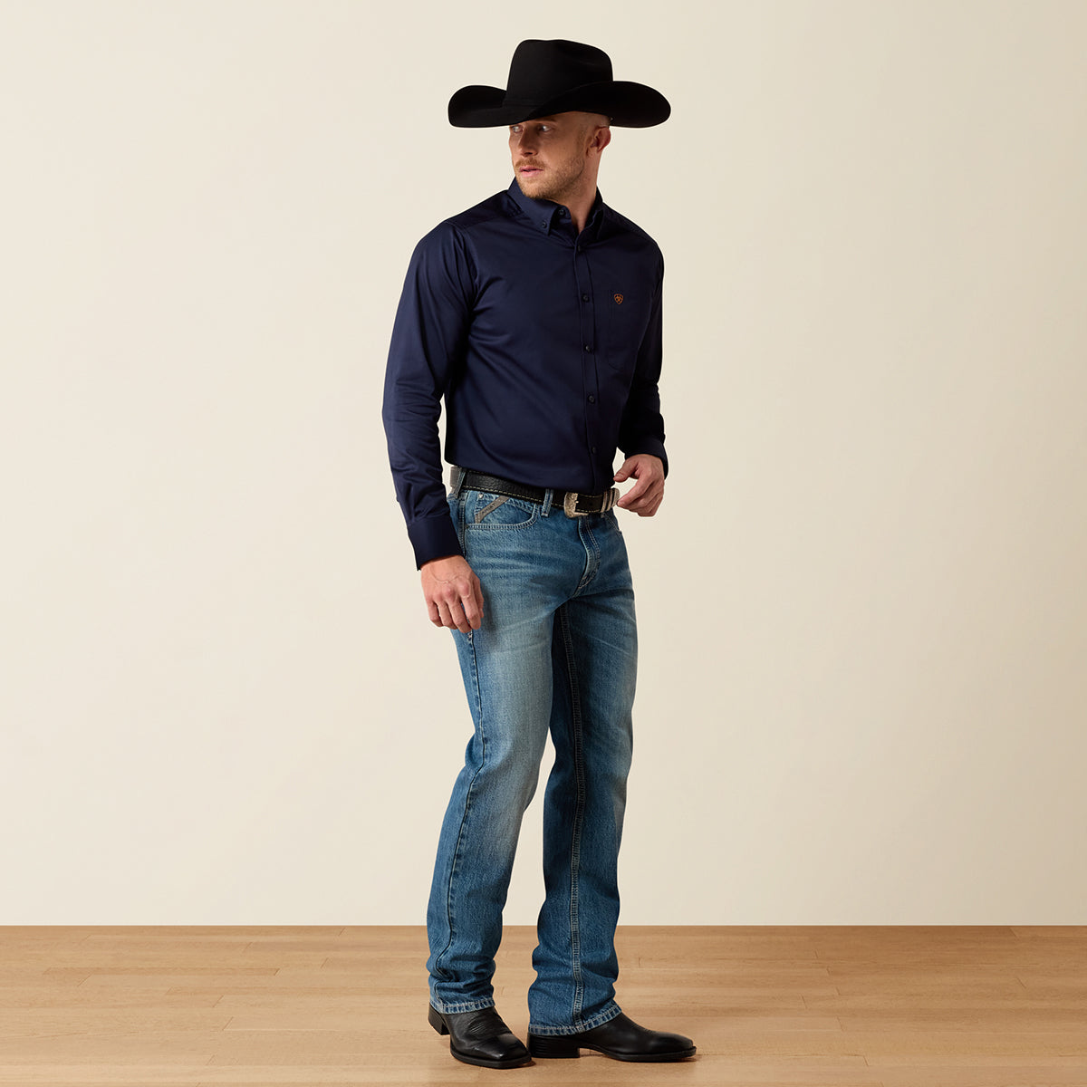 Front and full-length views of a man wearing the Ariat Men's Solid Twill long sleeve button-down shirt in Navy blue paired with jeans and cowboy hat.