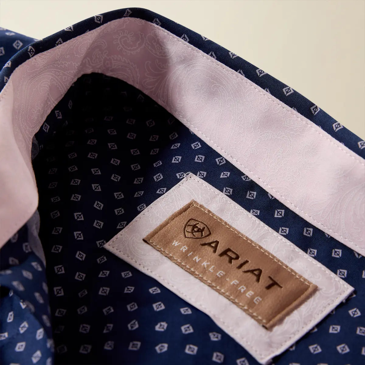 Close-up view of the inner neckband of the Ariat shirt displaying the Wrinkle-Free label and soft pink paisley contrast lining.