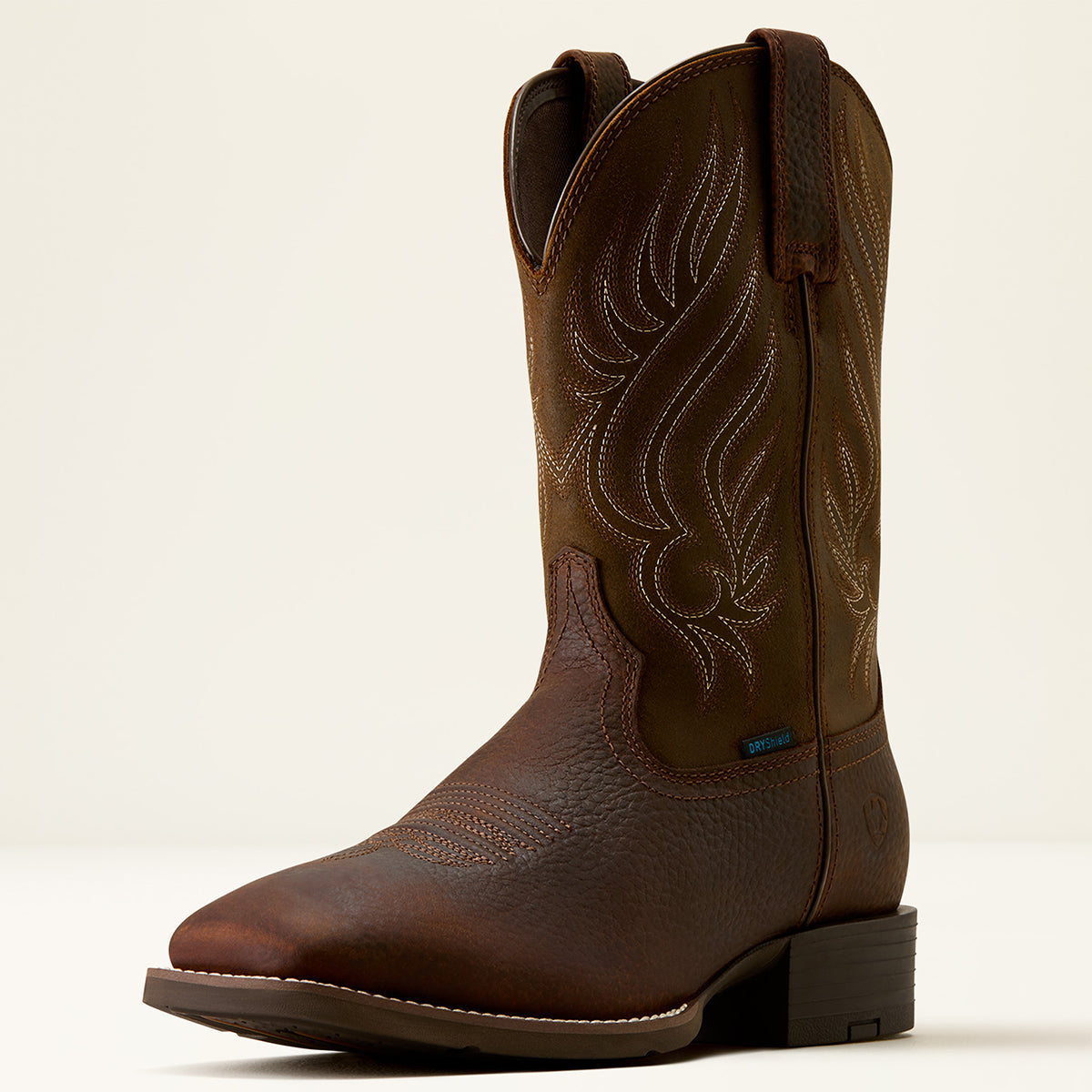Ariat men's dark brown leather square toe cowboy boot with decorative stitching on the shaft, shown from a three-quarter angle against a light beige background.