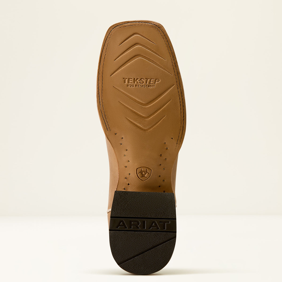 The outsole of an Ariat boot shown from a top-down view, featuring a tan textured TEKSTEP rubber sole and a black heel cap with the brand name ARIAT.
