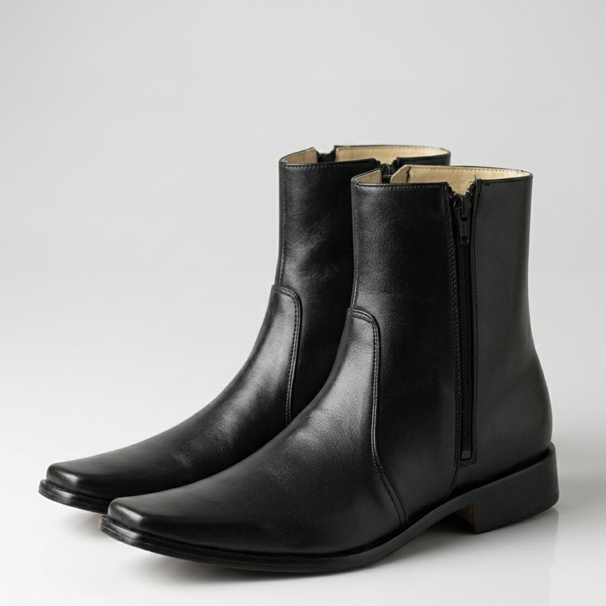 Pair of black leather ankle boots on a light gray background.