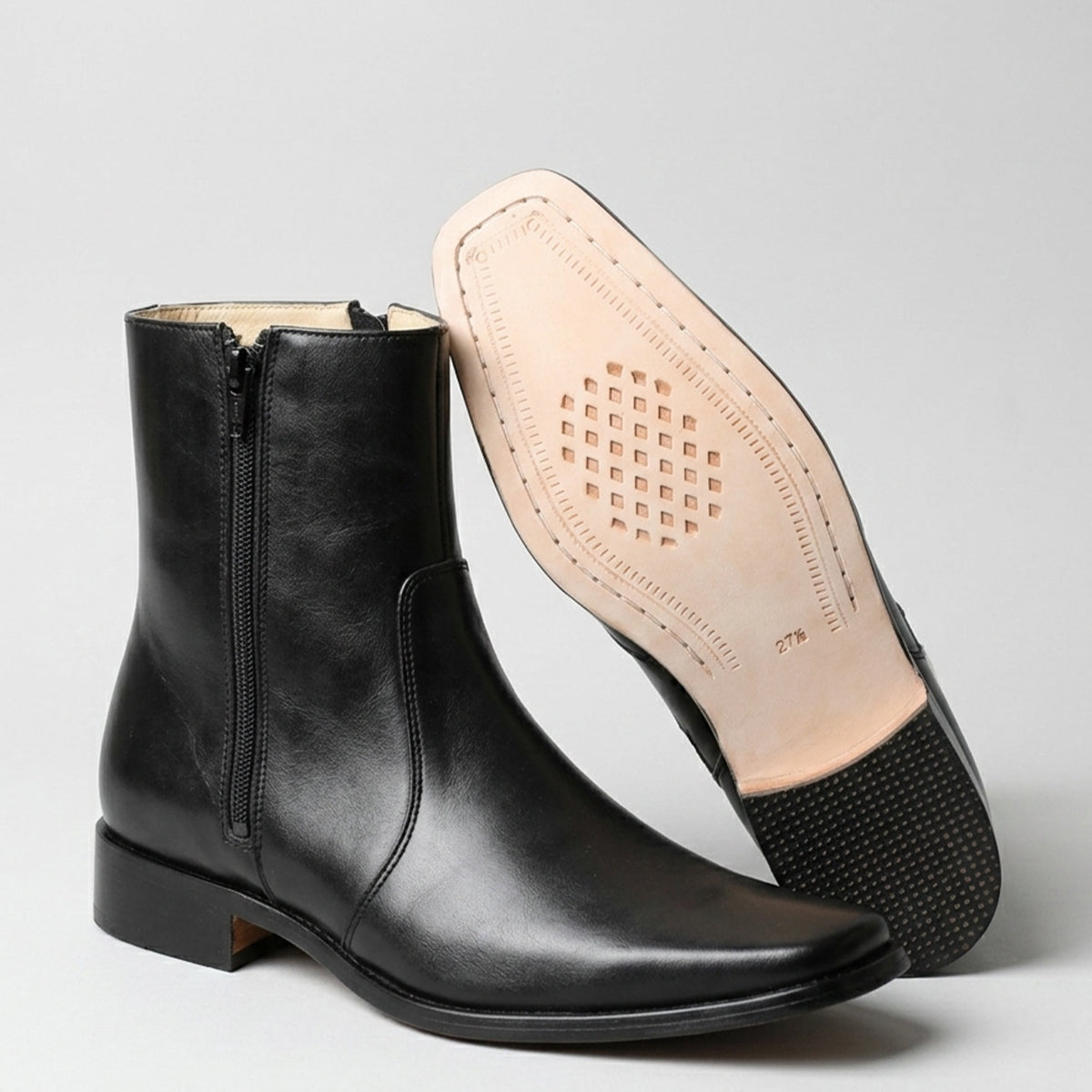 Black leather boot with a focus on the sole and insole on a gray background.