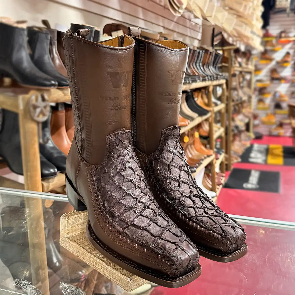 In-store display shot of the Wild West faded tobacco pirarucu zipper boots on a wooden stand.