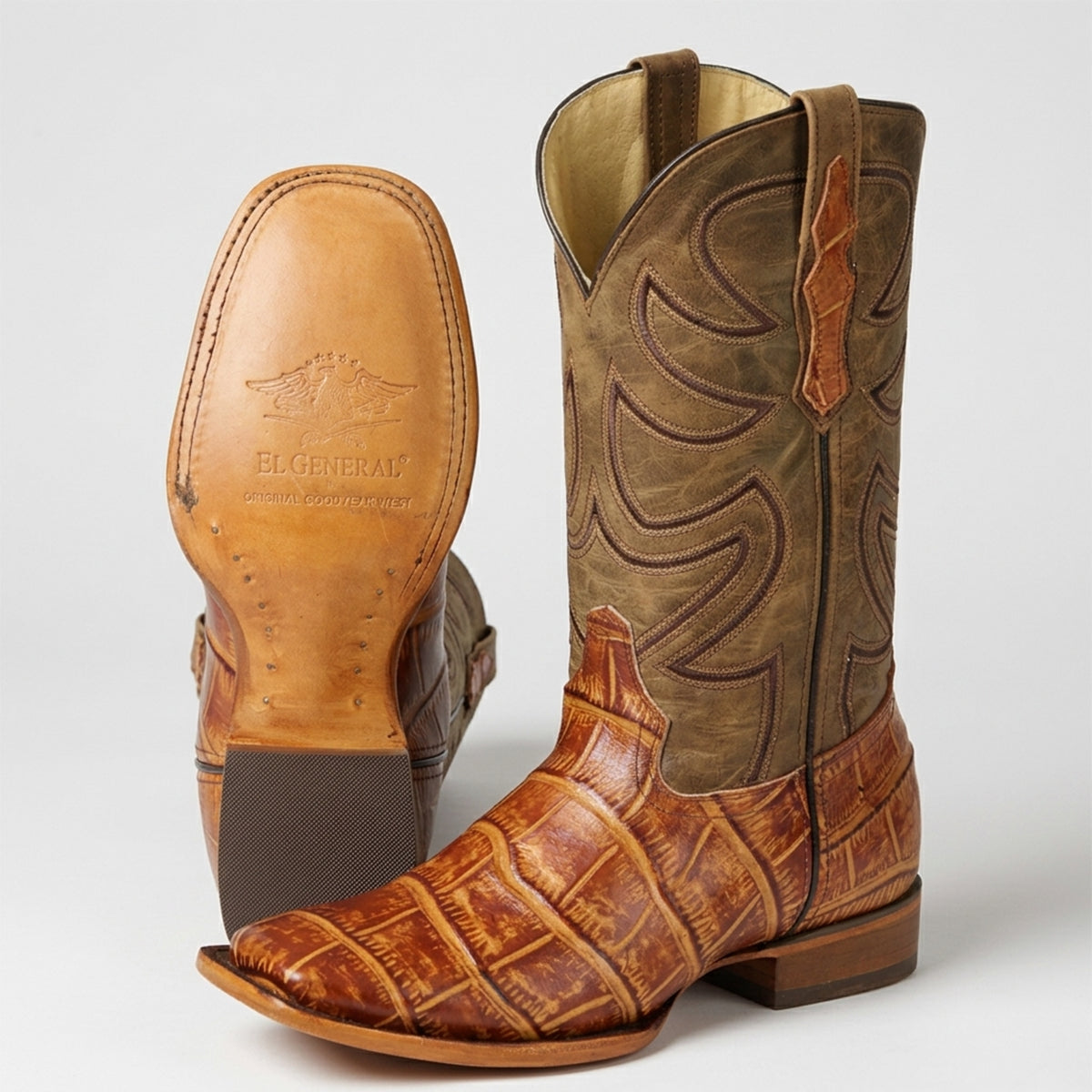 Pair of light brown Alligator print square toe cowboy boots with view of leather sole on a white background.
