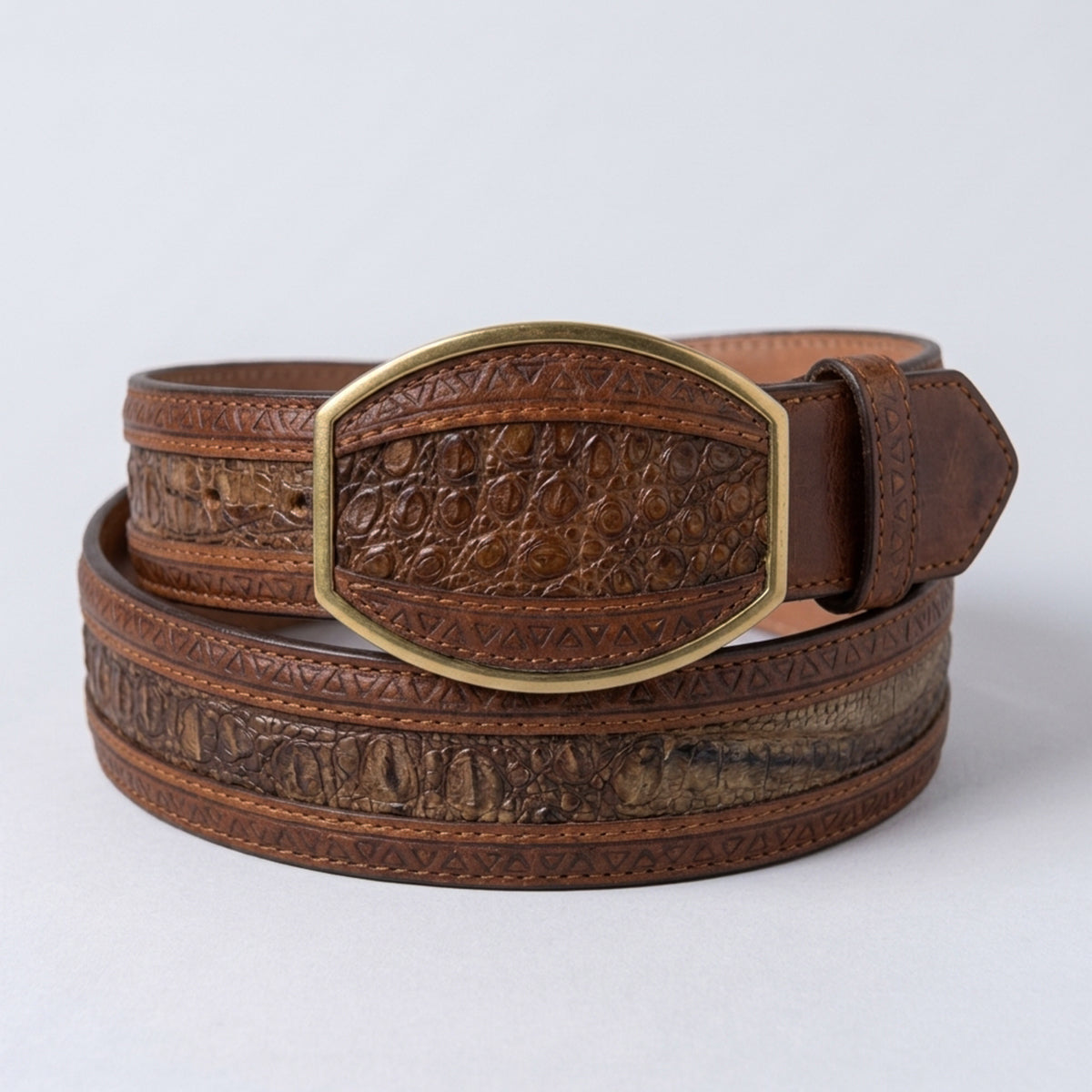 Los Altos men's Porto Oryx genuine caiman belly leather belt showing a rich cognac-brown center, laser-etched geometric borders, and a matching gold-tone inlay buckle.