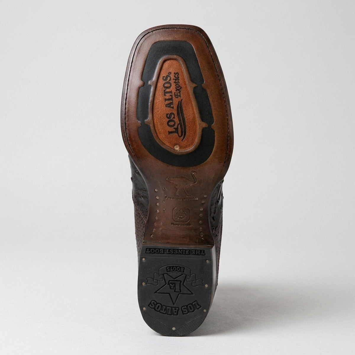 The outsole of a brown leather cowboy boot, showing the 'Los Altos Exotics' logo, photographed against a light gray background.