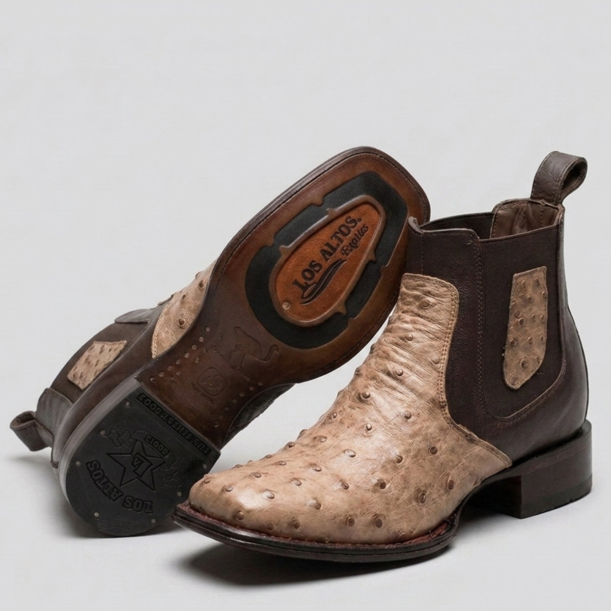 A pair of Los Altos western ankle boots featuring tan ostrich leather and dark brown leather panels, with one boot standing upright and the other tilted to show the sole.