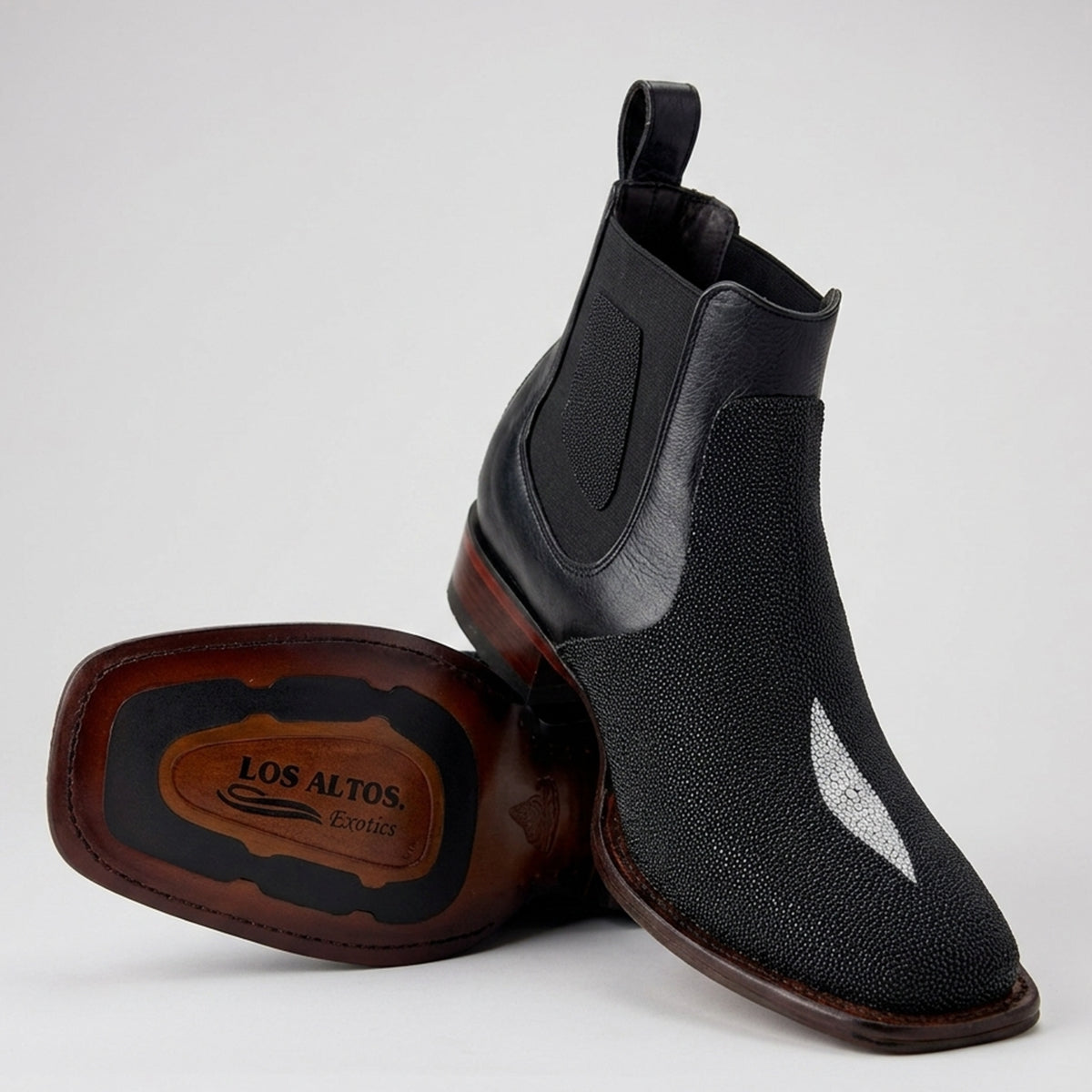 A pair of Los Altos men's black Stingray leather Chelsea boots, shown on a light gray background. One boot is standing upright while the other lies on its side to display the sole, which features the brand name 'Los Altos Boots'.