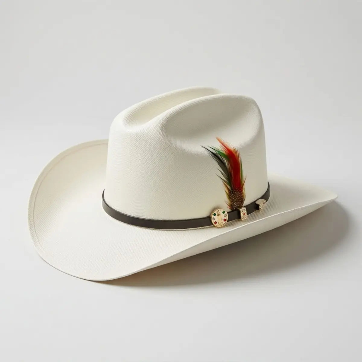 Angled studio view of the Abolengo Virgen de Guadalupe 1000X Chaparral straw cowboy hat displaying the off-white weave, black hatband, gold pin, and feather accent.