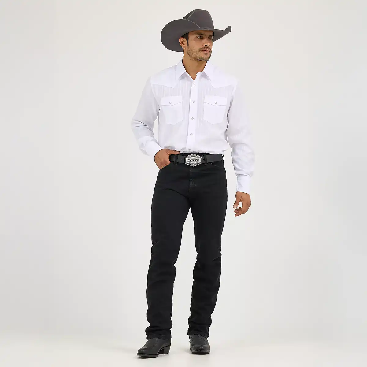 Full-length front view of a model wearing the Wrangler Cowboy Cut Silver Edition black slim fit jeans with a white Western shirt, gray cowboy hat, and silver belt buckle.