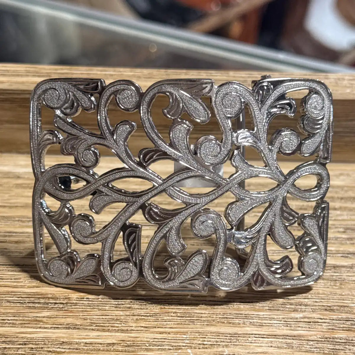Studio white background product photo of the stainless steel openwork belt buckle with floral vine filigree.