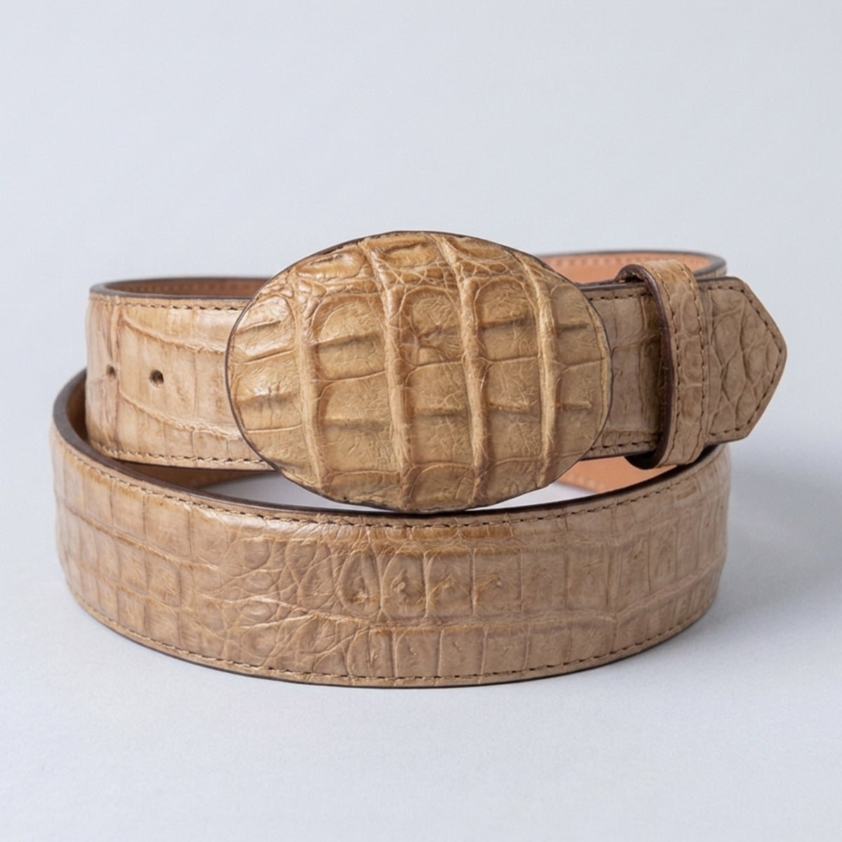 Los Altos men's greasy finish honey caiman leather belt showing a matte, oiled honey-tan scale texture and a matching oval leather-wrapped buckle.