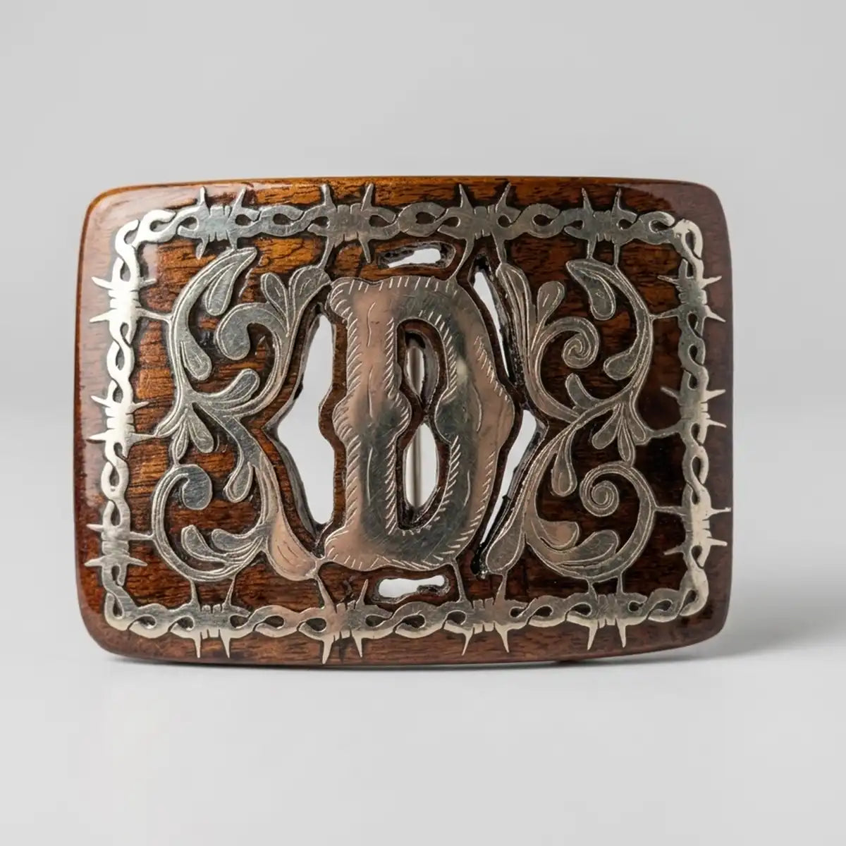 Front view of the handcrafted mesquite wood belt western buckle showing the metal Monogram D inlay and barbed wire frame on a light grey background.