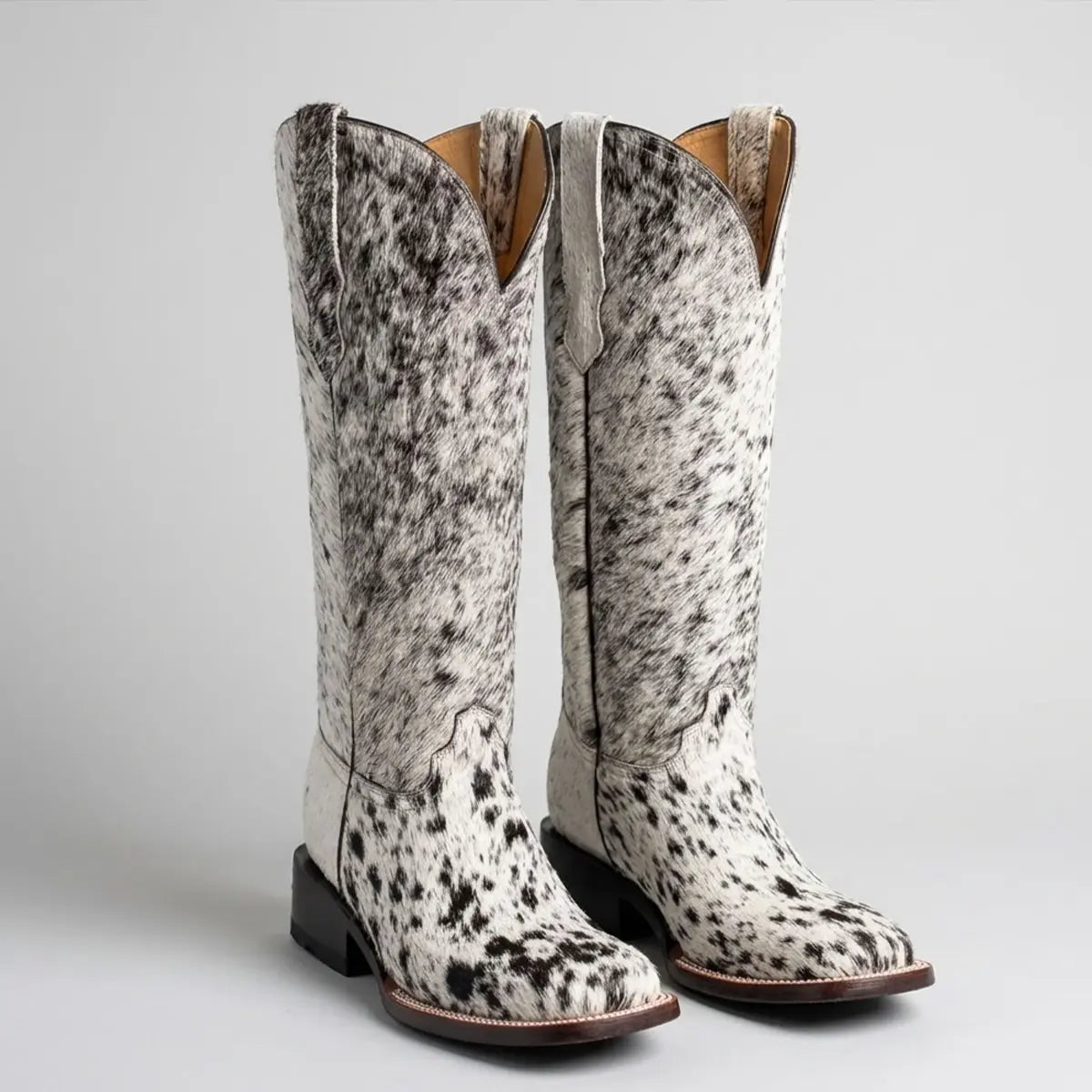 Pair of Botas Doble R women's cow hair-on hide western boots in a black and white spotted pattern, showcasing the square toe profile and matching dark leather heels.