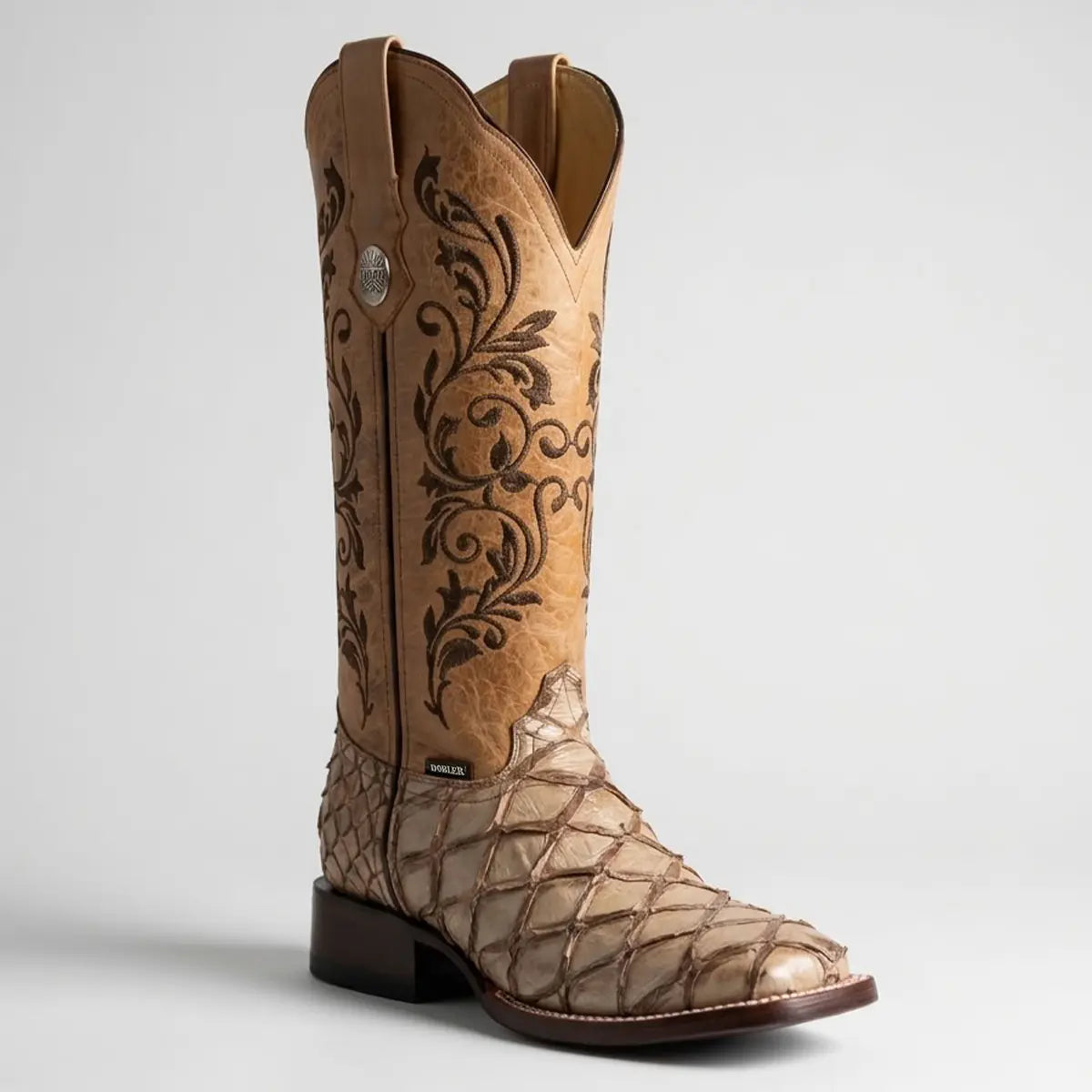 Single Botas Doble R women's cowgirl boot in a studio setting, highlighting the textured sand-colored pirarucu fish scale vamp, square toe, and tall 15-inch leather shaft with dark floral embroidery.