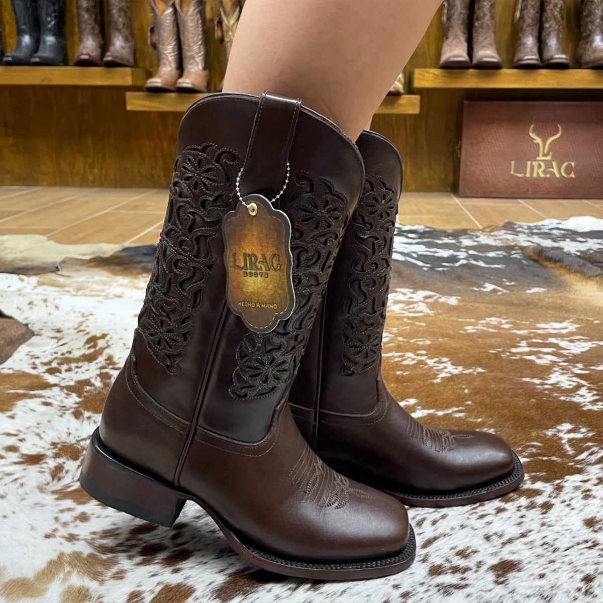 Lirac women's brown leather square toe cowgirl boots with decorative patterns and a visible brand tag on a textured floor.