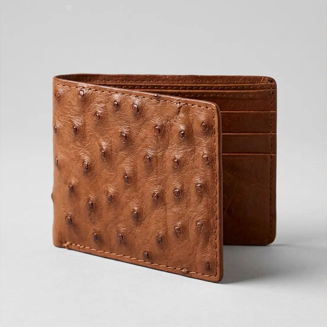 Studio view of the open Los Altos Cognac Full Quill Ostrich bifold wallet displaying the card slots, ID window, and genuine ostrich texture.