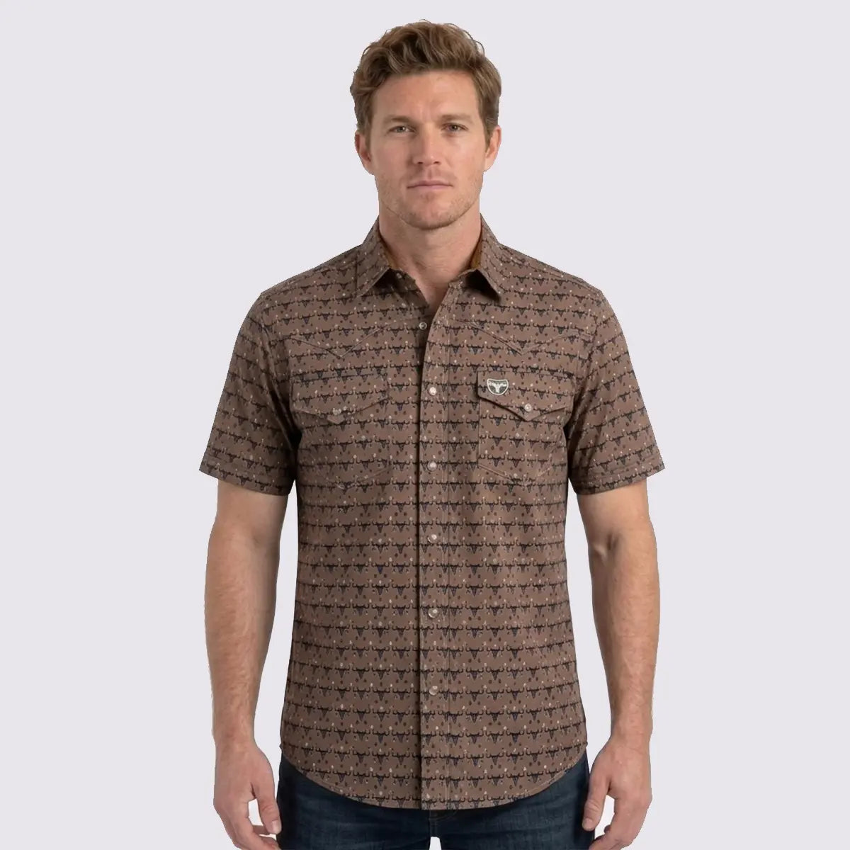 Front studio view of a male model wearing the Platini Men's camel brown Longhorn Heritage short sleeve technical performance Western shirt with dark denim.