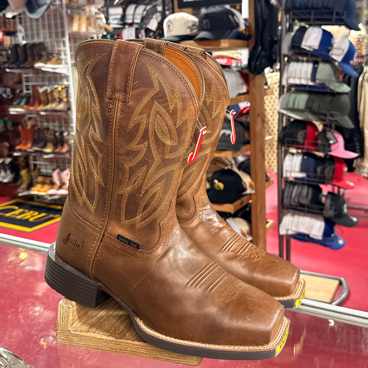 Men's Justin brown western steel toe work boots on display in a store.