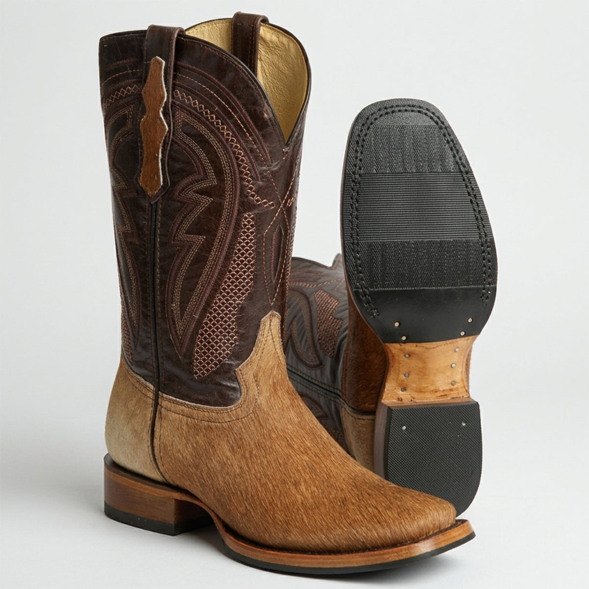 Pair of men's brown cowhide hair square toe western boots with detailed stitching on a white background.