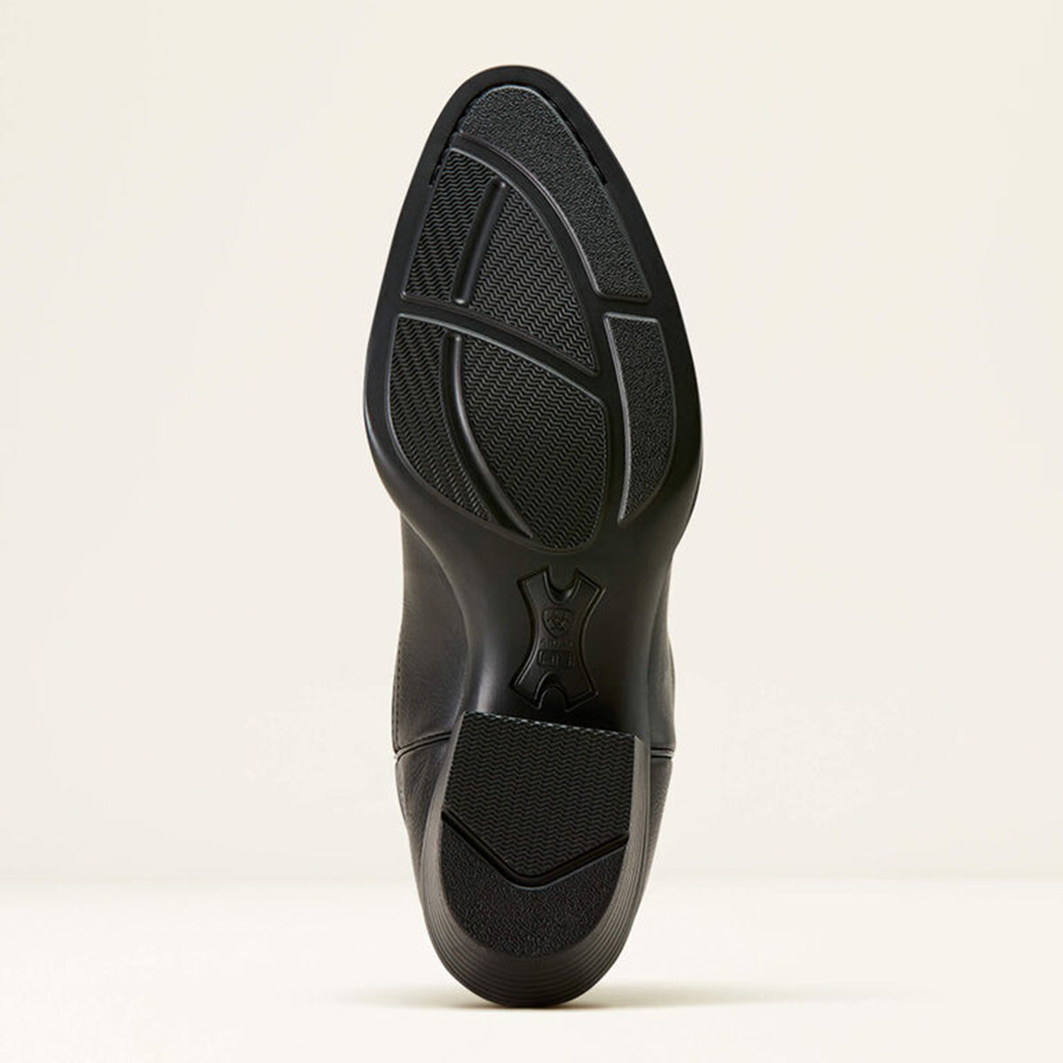 Ariat black boot sole on a light beige background.