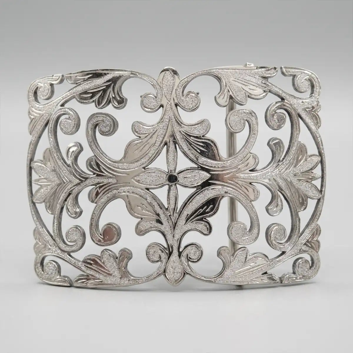 A silver filigree belt with an intricate openwork design featuring leaf and scroll motifs, photographed on a neutral gray background.