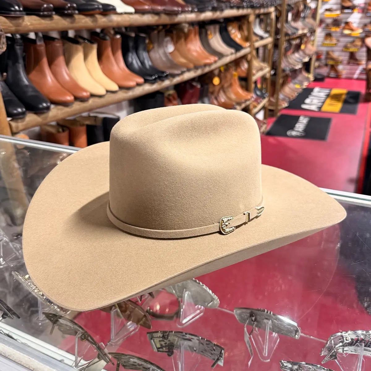 In-store glass counter view of the Stetson 6X Skyline fawn fur felt cowboy hat highlighting the Cattleman crown, self-felt hatband, and gold-tone buckle set.