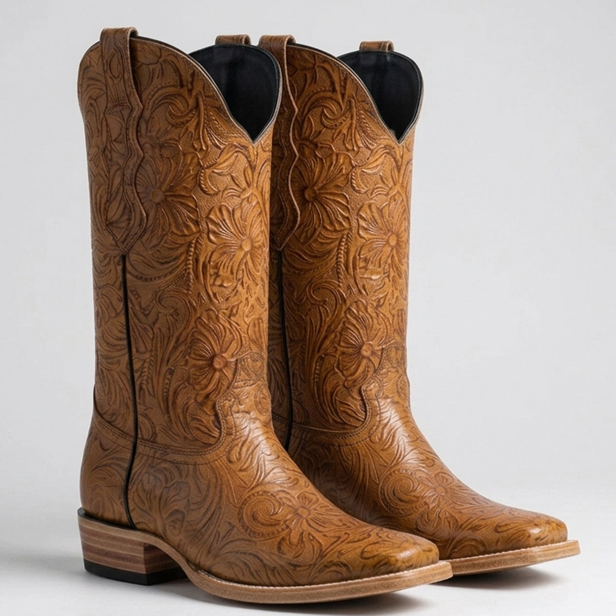 Women's tan western boots featuring an all-over floral tooled print leather pattern, square toe, tall shaft, and stacked leather western heel.