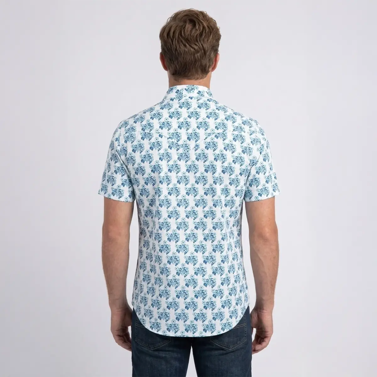 Back studio view of a male model wearing the Platini white short sleeve shirt showing the pointed Western back yoke and floral pattern.