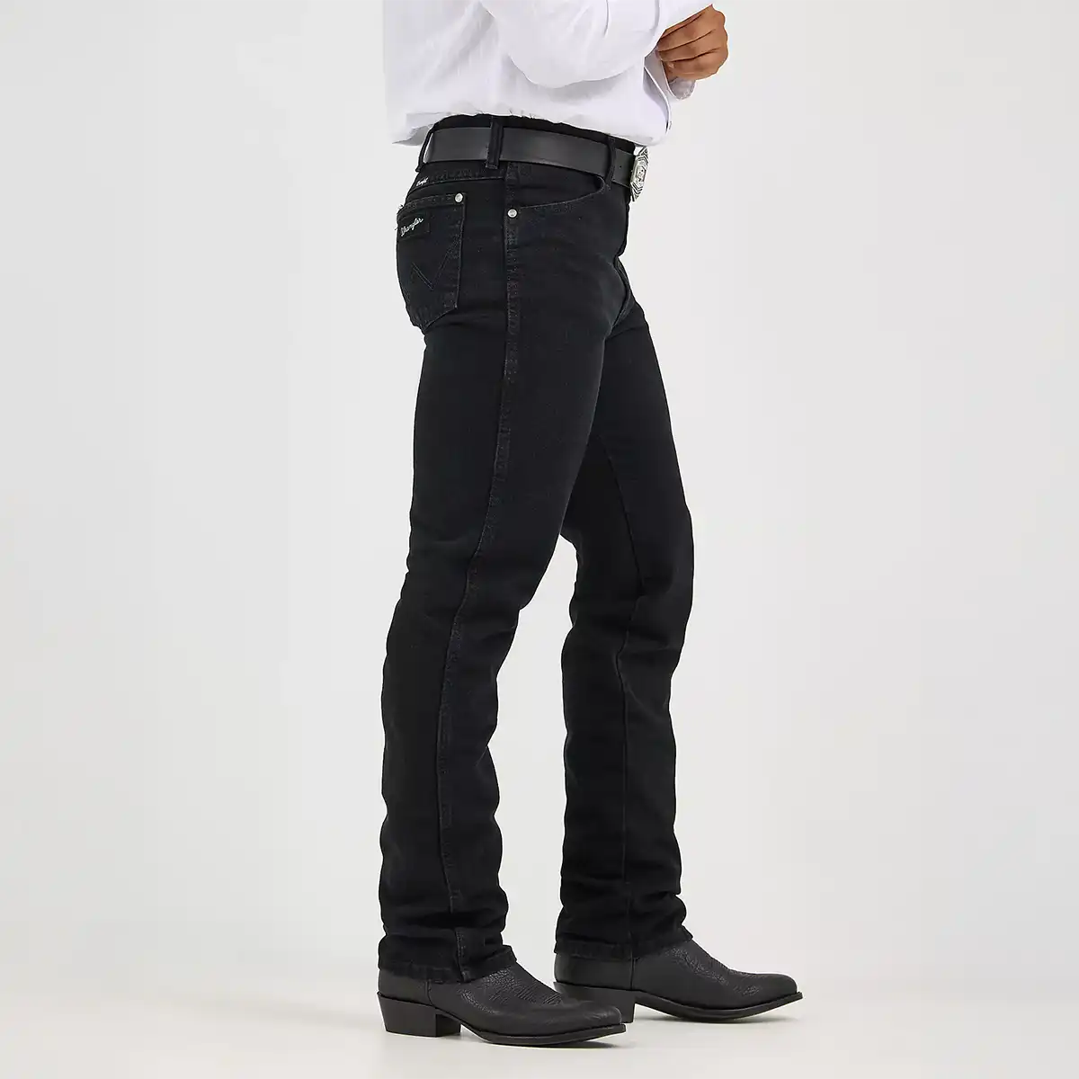 Side profile view of the Wrangler black slim fit jeans showing the clean tapered leg line over black leather cowboy boots.