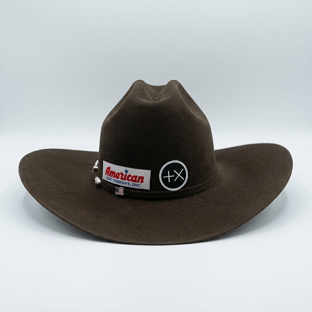Back view of American Hat Co brown western hat with a band featuring logos on a white background.
