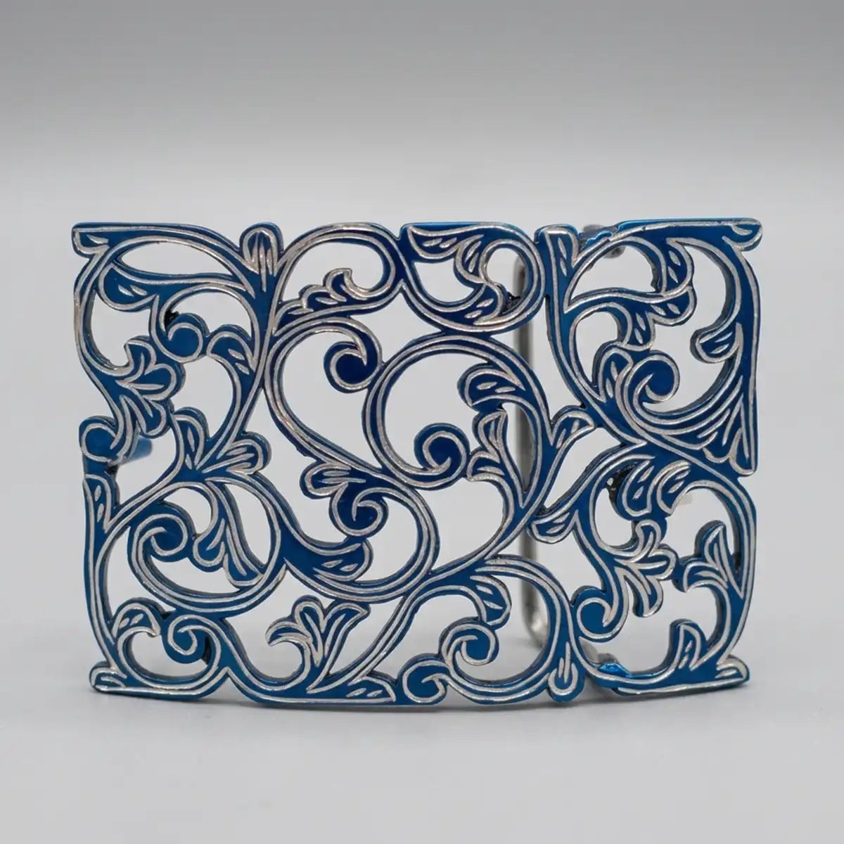 A decorative rectangular metal wall or screen panel featuring an intricate openwork scrollwork pattern in blue and silver, set against a neutral gray background.