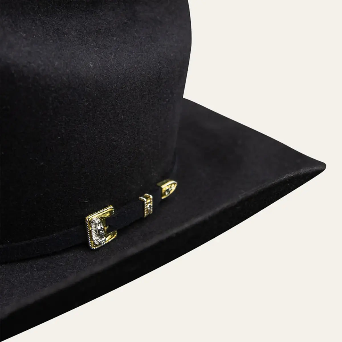 Close-up macro view of the Stetson 6X Guadalupana self-felt hatband featuring the gold and silver three-piece buckle set detailed with the Virgin of Guadalupe.