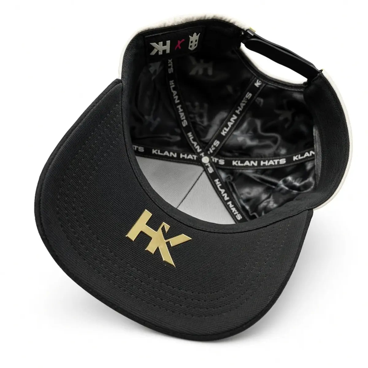 Inside view of the Klan Hats LA Chrome cap showcasing the black satin crown lining, branded taping, and metallic gold HK logo under the visor.